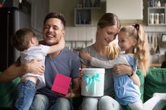 Niños de abarcamiento felices de la mamá y del papá que agradecen por cajas de regalo foto de archivo libre de regalías Niños de abarcamiento felices de la mamá y del papá que agradecen por cajas de regalo foto de archivo libre de regalías