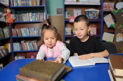 Niños en biblioteca que leen el libro interesante Aprendizaje de la niña y del muchacho fotos de archivo libres de regalías Niños en biblioteca que leen el libro interesante Aprendizaje de la niña y del muchacho fotos de archivo libres de regalías