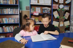 Niños en biblioteca que leen el libro interesante Aprendizaje de la niña y del muchacho imágenes de archivo libres de regalías Niños en biblioteca que leen el libro interesante Aprendizaje de la niña y del muchacho imágenes de archivo libres de regalías