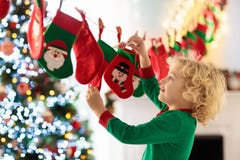Niños que abren regalos de Navidad Niño que busca para el caramelo y los regalos en calendario del advenimiento el mañana del inv foto de archivo Niños que abren regalos de Navidad Niño que busca para el caramelo y los regalos en calendario del advenimiento el mañana del inv foto de archivo