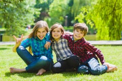 Niños sonrientes que se divierten en la hierba Niños que juegan al aire libre en verano los adolescentes comunican al aire libre imagen de archivo libre de regalías Niños sonrientes que se divierten en la hierba Niños que juegan al aire libre en verano los adolescentes comunican al aire libre imagen de archivo libre de regalías
