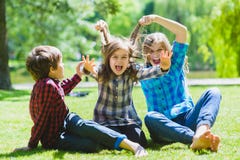 Niños sonrientes que se divierten en la hierba Niños que juegan al aire libre en verano los adolescentes comunican al aire libre imagenes de archivo Niños sonrientes que se divierten en la hierba Niños que juegan al aire libre en verano los adolescentes comunican al aire libre imagenes de archivo
