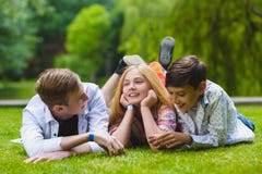 Niños sonrientes que se divierten en la hierba Niños que juegan al aire libre en verano los adolescentes comunican al aire libre imagenes de archivo Niños sonrientes que se divierten en la hierba Niños que juegan al aire libre en verano los adolescentes comunican al aire libre imagenes de archivo