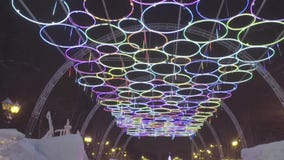 Noche del invierno en el parque del hielo Pueblo de la nieve La gente y el bebé caminan en ciudad del hielo durante las nevadas J Noche del invierno en el parque del hielo Pueblo de la nieve La gente y el bebé caminan en ciudad del hielo durante las nevadas J