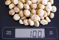 Noci di macadamia sulla scala digitale fotografia stock libera da diritti Noci di macadamia sulla scala digitale fotografia stock libera da diritti