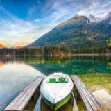 Noite fantástica do outono no lago Hintersee Poucos barcos no LAK imagem de stock Noite fantástica do outono no lago Hintersee Poucos barcos no LAK imagem de stock