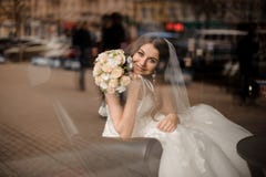 Noiva de sorriso que senta-se em uma cadeira preta de couro perto da janela fotografia de stock Noiva de sorriso que senta-se em uma cadeira preta de couro perto da janela fotografia de stock