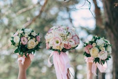 A noiva e seus amigos guardaram seus ramalhetes do casamento nas mãos imagem de stock A noiva e seus amigos guardaram seus ramalhetes do casamento nas mãos imagem de stock