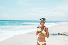 Noix de coco potable de femme sur la plage tropicale image libre de droits Noix de coco potable de femme sur la plage tropicale image libre de droits