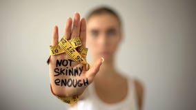 Non scarno abbastanza scritti sulla palma della donna con nastro adesivo, dieta severa, anoressia fotografie stock Non scarno abbastanza scritti sulla palma della donna con nastro adesivo, dieta severa, anoressia fotografie stock