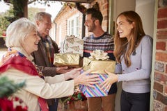 Nonni che sono accolti dalla famiglia come arrivano per la visita sul giorno di Natale con i regali fotografia stock libera da diritti Nonni che sono accolti dalla famiglia come arrivano per la visita sul giorno di Natale con i regali fotografia stock libera da diritti