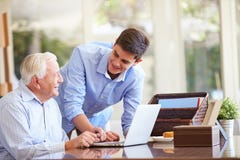 Nonno d'aiuto del nipote adolescente con il computer portatile immagine stock libera da diritti Nonno d'aiuto del nipote adolescente con il computer portatile immagine stock libera da diritti