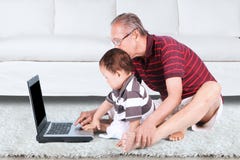 Nonno e nipote che per mezzo di un computer portatile immagine stock libera da diritti Nonno e nipote che per mezzo di un computer portatile immagine stock libera da diritti