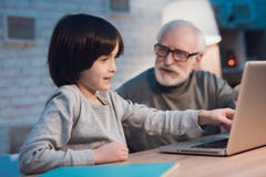 Nonno e nipote che si siedono sul computer portatile alla notte a casa fotografia stock libera da diritti Nonno e nipote che si siedono sul computer portatile alla notte a casa fotografia stock libera da diritti