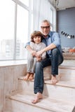 Nonno piacevole e nipote contentissimi che si siedono sulle scale fotografia stock Nonno piacevole e nipote contentissimi che si siedono sulle scale fotografia stock