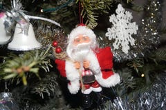 A small Santa Claus was hung on in the fir tree, on one side there are small bells and on the other side flake of Christmas. Front royalty free stock image A small Santa Claus was hung on in the fir tree, on one side there are small bells and on the other side flake of Christmas. Front royalty free stock image
