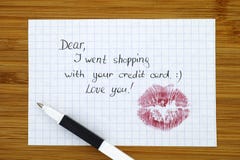 Note - Dear, I went shopping with your credit card. Love you! w. Ith kiss and pen. Wooden background Stock Images Note - Dear, I went shopping with your credit card. Love you! w. Ith kiss and pen. Wooden background Stock Images