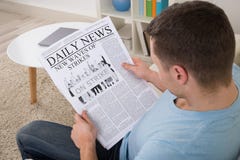 Notizie della lettura dell'uomo sul giornale a casa fotografia stock Notizie della lettura dell'uomo sul giornale a casa fotografia stock