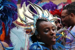 NOTTING HILL, LONDON - AUGUST 27, 2018: Woman with golden headpiece with feathers in her costume participates in Notting Hill Carn royalty free stock photo NOTTING HILL, LONDON - AUGUST 27, 2018: Woman with golden headpiece with feathers in her costume participates in Notting Hill Carn royalty free stock photo