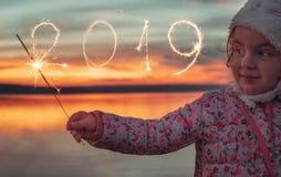 Nouvelle année 2019 et belle fille avec des cierges magiques sur le lac au coucher du soleil images stock Nouvelle année 2019 et belle fille avec des cierges magiques sur le lac au coucher du soleil images stock