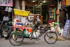 Nova Deli, Índia 10 de abril de 2016: Homem não identificado que fuma com seus povos de espera do riquexó em Paharganj Imagem de Stock Royalty Free Nova Deli, Índia 10 de abril de 2016: Homem não identificado que fuma com seus povos de espera do riquexó em Paharganj Imagem de Stock Royalty Free