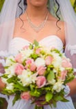 Novia con una pulsera alrededor del cuello que sostiene las flores fotografía de archivo Novia con una pulsera alrededor del cuello que sostiene las flores fotografía de archivo