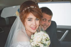 Novia joven en un coche de la boda con el ramo de la boda Pares felices imagen de archivo Novia joven en un coche de la boda con el ramo de la boda Pares felices imagen de archivo