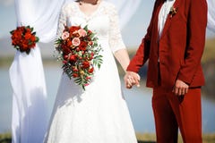 Nozze nel colore di Marsala di stile Sposa e sposo che si tengono per mano all'altare Immagine Stock Libera da Diritti Nozze nel colore di Marsala di stile Sposa e sposo che si tengono per mano all'altare Immagine Stock Libera da Diritti