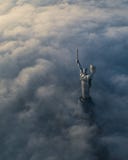 Nubes gruesas de la niebla del otoño y del monumento de la patria que se pega fuera de ellos fotos de archivo libres de regalías Nubes gruesas de la niebla del otoño y del monumento de la patria que se pega fuera de ellos fotos de archivo libres de regalías