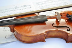 Nuevo violín de madera marrón con un arco puesto a lo largo del instrumento de música y de una partitura bajo ella imágenes de archivo libres de regalías Nuevo violín de madera marrón con un arco puesto a lo largo del instrumento de música y de una partitura bajo ella imágenes de archivo libres de regalías