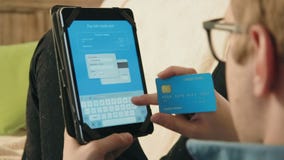 Numero di carta di credito di riempimento del giovane sulla sua compressa digitale che paga l'acquisto online Numero di carta di credito di riempimento del giovane sulla sua compressa digitale che paga l'acquisto online