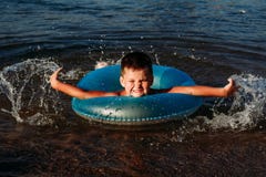 Nuotate allegre del bambino nel mare con un cerchio di gomma blu fotografia stock Nuotate allegre del bambino nel mare con un cerchio di gomma blu fotografia stock