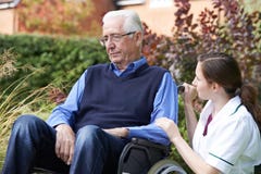 Nurse Comforting Senior Man In Wheelchair stock photo Nurse Comforting Senior Man In Wheelchair stock photo