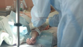 Nurse in gloves and mask putting female patient on a drip in a hospital ward stock footage Nurse in gloves and mask putting female patient on a drip in a hospital ward stock footage