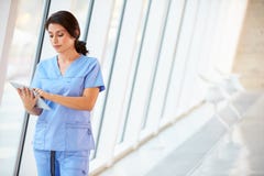 Nurse Using Digital Tablet In Corridor Of Modern Hospital stock photo Nurse Using Digital Tablet In Corridor Of Modern Hospital stock photo