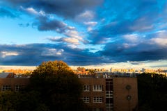 Nuvole drammatiche che si muovono attraverso un cielo blu, mentre il tramonto aggiunge un'incandescenza dorata all'ambiente urban fotografie stock libere da diritti Nuvole drammatiche che si muovono attraverso un cielo blu, mentre il tramonto aggiunge un'incandescenza dorata all'ambiente urban fotografie stock libere da diritti