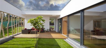 Ny fridsam modernt hem med privatträdgården och terrass royaltyfri bild Ny fridsam modernt hem med privatträdgården och terrass royaltyfri bild