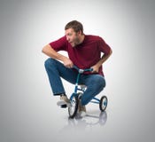 Nyfiken man på barns cykel arkivfoto Nyfiken man på barns cykel arkivfoto