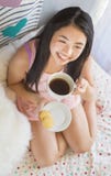 Nätt asiatisk ung kvinna som har frukosten i säng arkivbilder Nätt asiatisk ung kvinna som har frukosten i säng arkivbilder