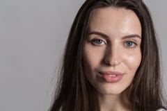 Nätt kvinna med fluffigt hår, påklädd tillfälligt mot en grå studiovägg royaltyfri bild Nätt kvinna med fluffigt hår, påklädd tillfälligt mot en grå studiovägg royaltyfri bild