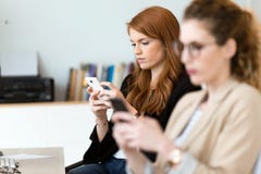 Nätt ung affärskvinna som använder hennes mobiltelefon i kontoret arkivfoto Nätt ung affärskvinna som använder hennes mobiltelefon i kontoret arkivfoto
