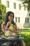 Nätt ung kvinna som dricker ny lemonad i trädgården, produktfotografi för restaurangen, ny lemonad för sommar arkivbild Nätt ung kvinna som dricker ny lemonad i trädgården, produktfotografi för restaurangen, ny lemonad för sommar arkivbild