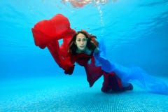 O adolescente nada debaixo d'água na associação em um fundo azul e olha a câmera Retrato Tiro sob a água imagem de stock O adolescente nada debaixo d'água na associação em um fundo azul e olha a câmera Retrato Tiro sob a água imagem de stock