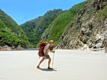 O ancião anda na praia com uma trouxa Fotos de Stock O ancião anda na praia com uma trouxa Fotos de Stock