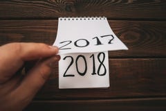 O ano novo 2018 é conceito de vinda A mão lança a folha do bloco de notas na tabela de madeira 2017 estão girando, 2018 estão abr foto de stock O ano novo 2018 é conceito de vinda A mão lança a folha do bloco de notas na tabela de madeira 2017 estão girando, 2018 estão abr foto de stock