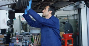O auto mecânico no serviço do carro, reparos do especialista o carro, faz a transmissão e as rodas Conceito: reparo das máquinas, fotografia de stock O auto mecânico no serviço do carro, reparos do especialista o carro, faz a transmissão e as rodas Conceito: reparo das máquinas, fotografia de stock