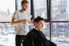 O cabeleireiro faz o cabelo com o pente do cliente satisfeito considerável no salão de beleza profissional do cabeleireiro imagens de stock royalty free O cabeleireiro faz o cabelo com o pente do cliente satisfeito considerável no salão de beleza profissional do cabeleireiro imagens de stock royalty free