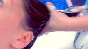 O cabelo do cliente da lavagem do barbeiro no salão de beleza no dissipador video estoque O cabelo do cliente da lavagem do barbeiro no salão de beleza no dissipador video estoque