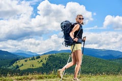 O caminhante da mulher que caminha no monte gramíneo, trouxa vestindo, usando trekking cola nas montanhas foto de stock royalty free O caminhante da mulher que caminha no monte gramíneo, trouxa vestindo, usando trekking cola nas montanhas foto de stock royalty free