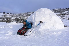 O caminhante derrama-se um chá de uma garrafa térmica, sentando-se em um iglu nevado da cabana imagens de stock O caminhante derrama-se um chá de uma garrafa térmica, sentando-se em um iglu nevado da cabana imagens de stock
